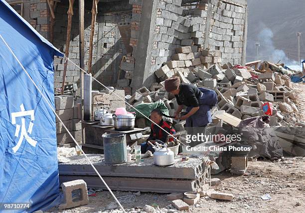 Tibetan survivor makes a pigtail for her daughter on the debris of her home destroyed in the Yushu earthquake at the Jiegu Township on April 26, 2010...
