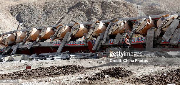 Tibetan survivor walks past the prayer wheels destroyed in the Yushu earthquake at the Changu Temple of Jiegu Township on April 26, 2010 in Yushu...