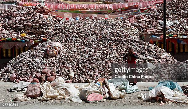 Tibetan monk makes a phone call in front of the debris of Mani stone town destroyed in the Yushu earthquake at the Jiegu Township on April 26, 2010...