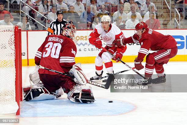 Valtteri Filppula of the Detroit Red Wings passes the puck through the Coyotes crease while being defended by Zbynek Michalek of the Phoenix Coyotes...