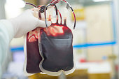 Red blood bag in hand scientist over white background in laboratory.