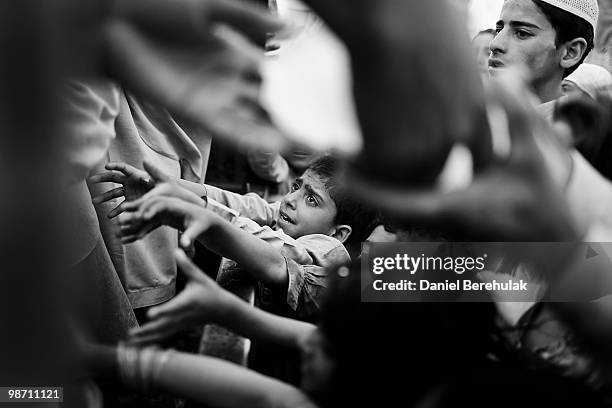 Young children, internally displaced due to the Pakistan Army's offensive against the Taliban, in Swat and Buner, scramble to get pieces of ice being...