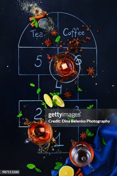 coffee and tea hopscotch game. choosing a drink creative food photography concept. flat lay with a chalk hopscotch outline on a dark background and cups of tea and coffee with dynamic splashes. - khabarovsk krai stockfoto's en -beelden