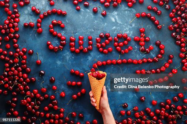 fresh cherries in a waffle ice cream cone forming a word sweet on a stone background with copy space. food typography or food lettering concept with ripe berries - khabarovsk krai stockfoto's en -beelden