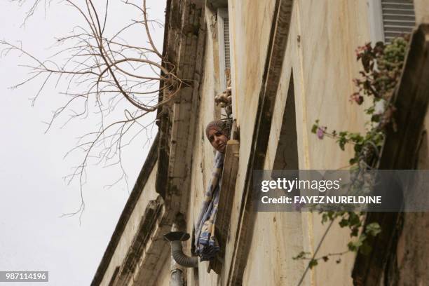 An Algerian woman looks on from her house's window in the historical Casbah distrisct in Algiers City 25 May 2006. Once a sparkling white medina, or...