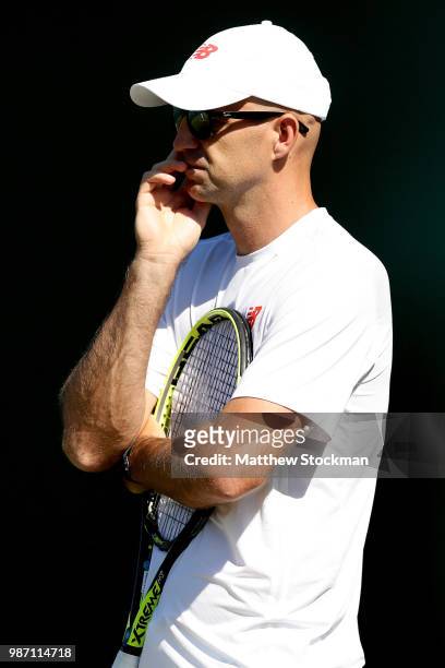 Ivan Ljubicic watches Roger Federer of Switzerland practice on court during training for the Wimbledon Lawn Tennis Championships at the All England...