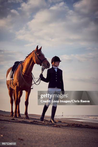 a young woman standing with her horse on the beach - riding habit stock pictures, royalty-free photos & images