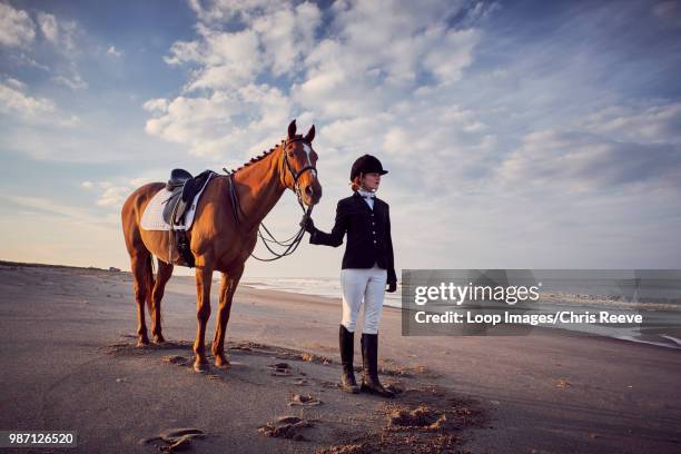 a young woman standing with her horse on the beach - jodhpurs stock pictures, royalty-free photos & images