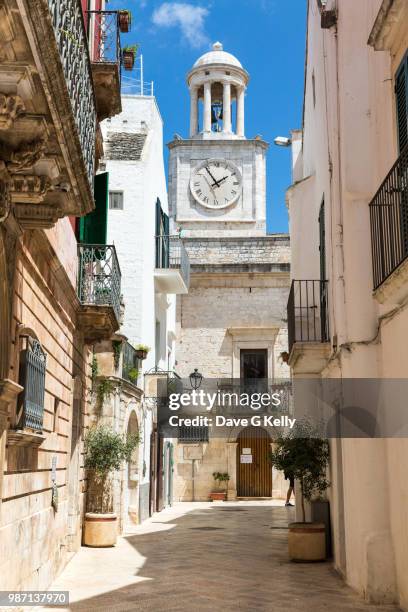 alley and clock tower in old italian town - cisternino stock-fotos und bilder