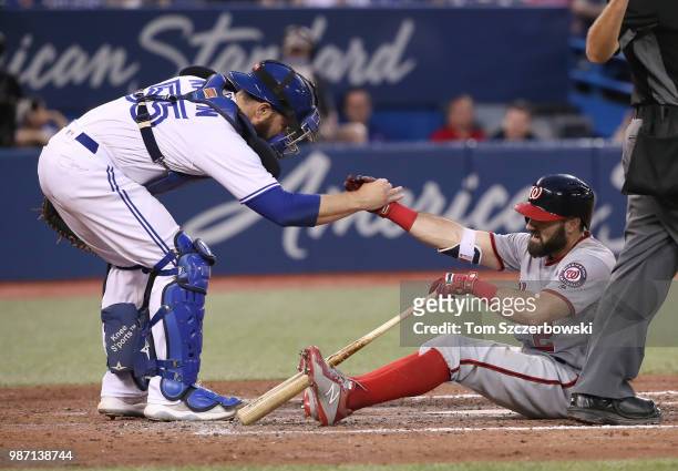 Adam Eaton of the Washington Nationals is helped up by Russell Martin of the Toronto Blue Jays after fouling a ball off his foot in the seventh...
