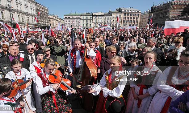 People dressed in traditional costumes play music and sing as people gather on Krakow's market square in front of the Basilica of Our Lady prior to...
