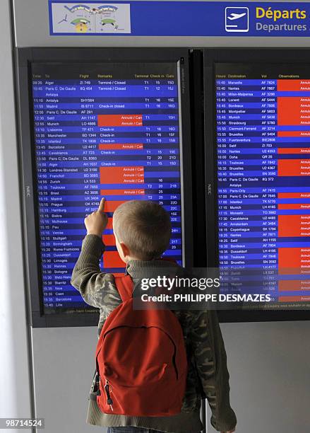 Young boy watches an electronic board announcing the cancelled flights in red, on April 20, 2010 at the Saint Exupery airport in Lyon, eastern...