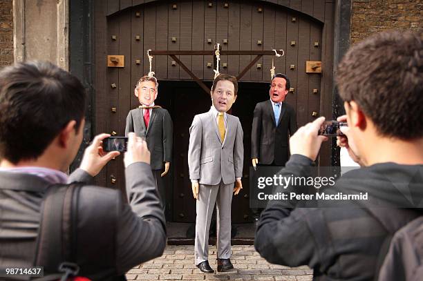 Two men take photographs of effigies of party leaders Gordon Brown, Nick Clegg and David Cameron hanging on a gallows outside the London Dungeon...