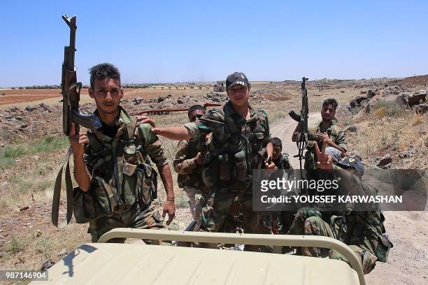 Syrian government forces' soldiers hold their weapons at the back of a pick-up truck during a government guided tour in the village of al-Sourah,...