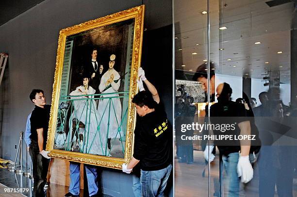 Chinese workers puts the French painting "Le balcon" by Edouard Manet behind secured glass as artworks from France's musee d'Orsay are unwrapped at...