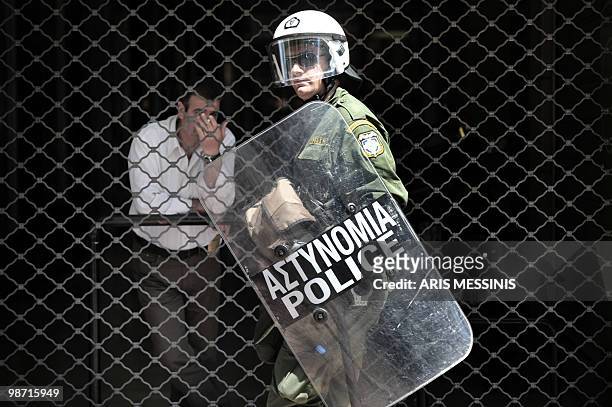 Riot police member walks in front of a protected store during a demonstration in central Athens on April 22, 2010. Greek civil servants today staged...