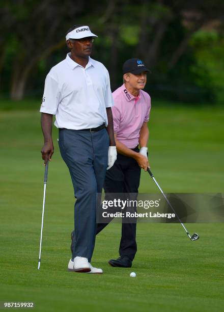 David Toms makes an approach shot on the 10th hole as Vijay Singh of Fiji looks on during round two of the U.S. Senior Open Championship at The...