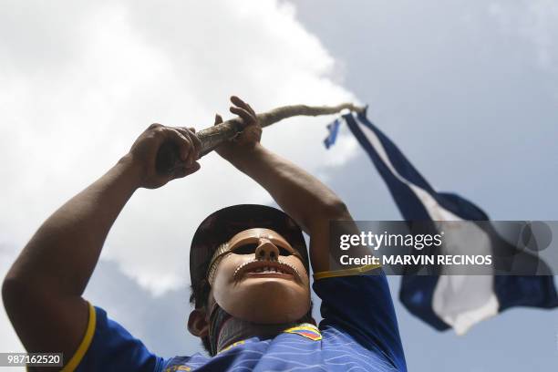 Masked protester flutters a Nicaraguan national flag in demand of Nicaraguan President Daniel Ortega's resignation and justice for those killed...