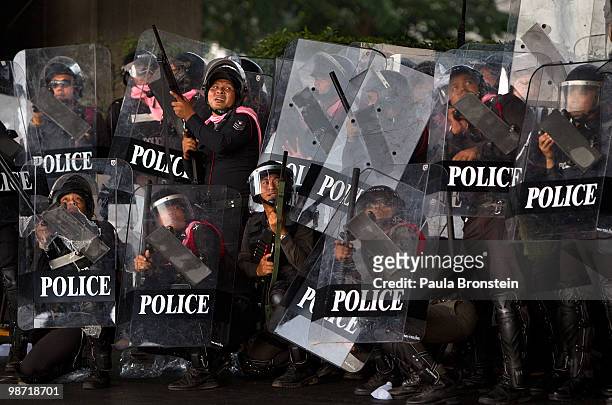 Members of the Thai military police shield themselves during a gun battle with red shirt protesters as violence flares outside the city on April 28,...