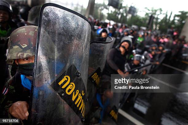 Members of the Thai military shield themselves during a gun battle with red shirt protesters as violence flares outside the city on April 28, 2010 in...
