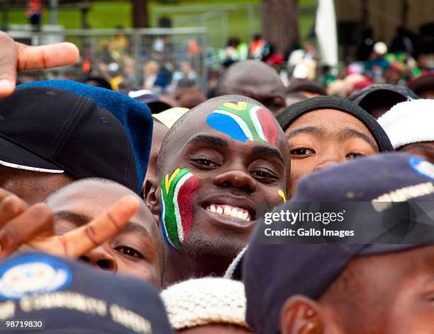 South African citizen with the national flag painted on his face smiles amongst the crowd during Freedom Day celebrations outside the Union Building...