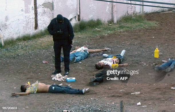 Police officer places markers next to the bodies of several men killed by drug traffickers in the bar in Ciudad Juarez, Mexico, on April 28, 2010....