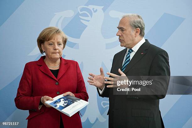 German Chancellor Angela Merkel talks to OECD Secretary-General Jose Angel Gurria during the handover of the OECD Report at the Chancellery on April...