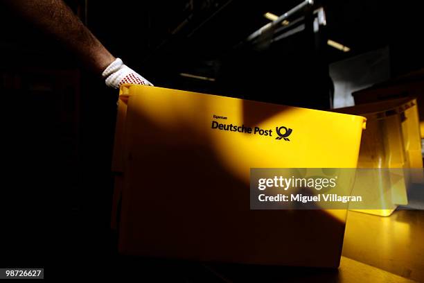 Man carries yellow boxes filled with letters at the Deutsche Post DHL sorting center on April 28, 2010 in Munich, Germany. Deutsche Post DHL held its...