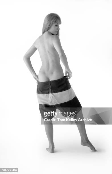 Back view of naked model as she pulls on a pair of boardshorts , 1966.