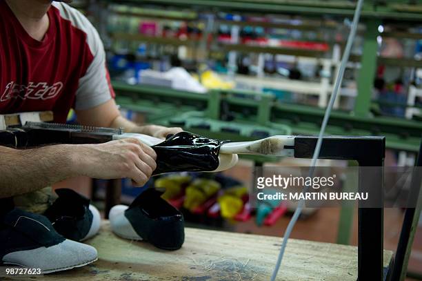 Man adjusts a pair of shoes at the Repetto workshop on March 25, 2010 in Saint-Medard d'Excideuil, central France. Repetto was founded in 1947 by...