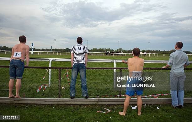 Competitors prepare for the "People's Cup" race at Kempton Park race track at Sunbury on Thames in Middlesex as watching riders take part in a horse...