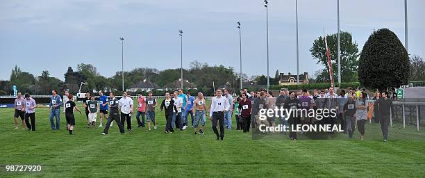 Competitors walk onto the track for the "People's Cup" race at Kempton Park race track at Sunbury on Thames in Middlesex on April 28, 2010. The race...