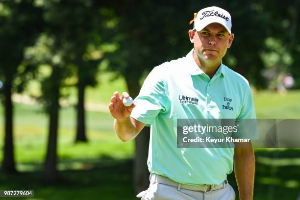 Bill Haas waves his ball to fans after making a par putt on the fourth hole green during the second round of the Quicken Loans National at TPC...