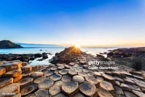 puesta de sol sobre la calzada del gigante, irlanda del norte - columna de basalto fotografías e imágenes de stock