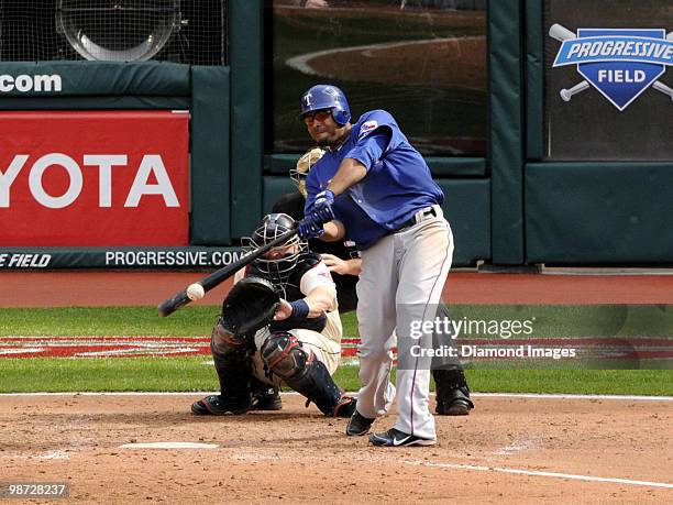 Outfielder Nelson Cruz of the Texas Rangers hits a pitch as catcher Mike Redmond of the Cleveland Indians and homeplate umpire Marvin Hudson look on...