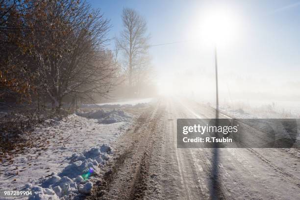 winter fog road with powerline post and direct sun - neige fondue photos et images de collection