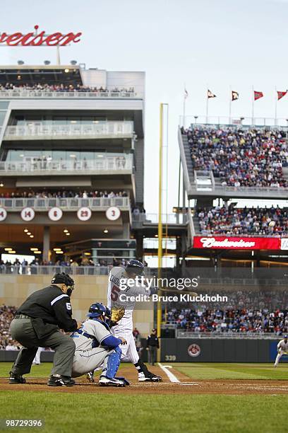 Michael Cuddyer of the Minnesota Twins hits the ball against the Kansas City Royals as Jason Kendall catches and umpire Eric Cooper watches on April...