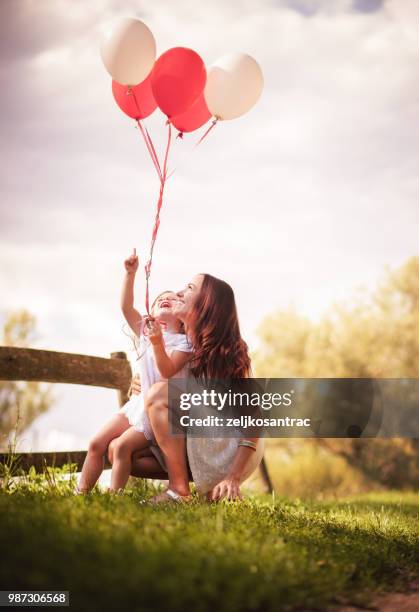 giovane donna con bambino in abito bianco con palloncini colorati all'aperto - mamma bambina palloncino bianco foto e immagini stock