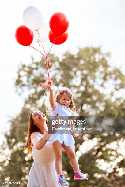 giovane donna con bambino in abito bianco con palloncini colorati all'aperto - mamma bambina palloncino bianco foto e immagini stock