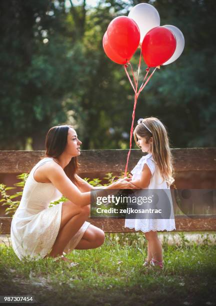 giovane donna con bambino in abito bianco con palloncini colorati all'aperto - mamma bambina palloncino bianco foto e immagini stock