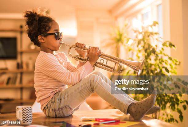 cool african american girl having fun while playing trumpet at home. - trumpet stock pictures, royalty-free photos & images