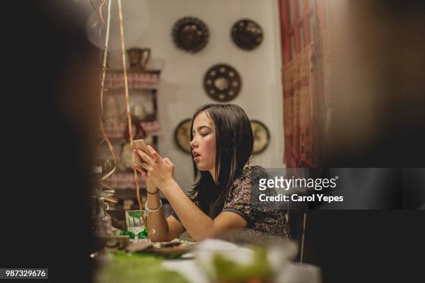 teenager using smartphone during party dinner at home - sólo una adolescente fotografías e imágenes de stock