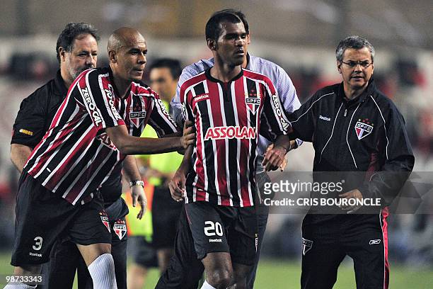Brazilian player Richarylson of Sao Paulo is escorted out of the pitch by teammate Alex Silva and staff members after he was expelled folloowing a...