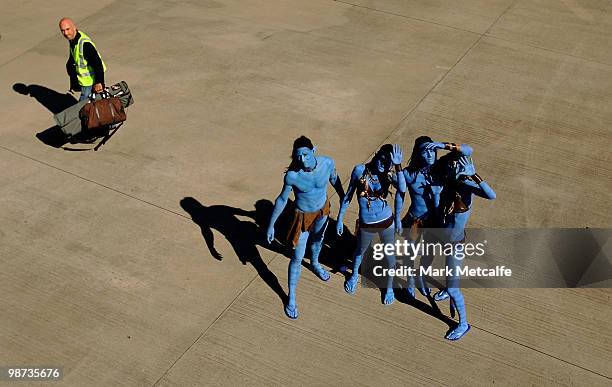 Models dressed up as characters from the film 'Avatar' pose on the tarmac as a baggage handler walks past during the launch of "AVATAR" Blu-ray and...