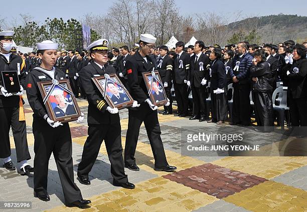 Choi Won-Il , captain of the sunken South Korean naval ship Cheonan, and the survivors hold portraits of the victims during a funeral ceremony at a...