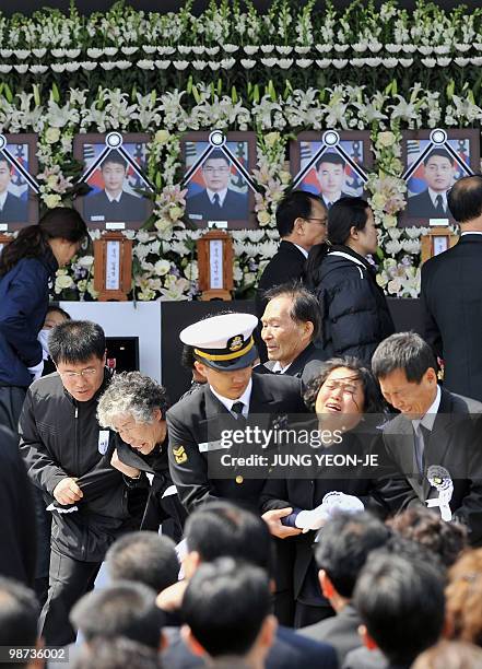 Relatives weep after laying flowers on an altar for the sailors who died when the South Korean warship Cheonan sank during a funeral ceremony at a...