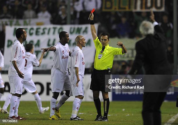 Referee Jorge Larrionda shows red card to player Pablo Guinazu as head coach Jorge Fossatti of Internacional reacts during a match between Banfield...