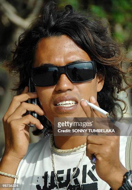 In this photograph taken on April 27, 2010 local surf instructor Rosnan Efendi talks on a mobile phone in Kuta beach on the resort island of Bali....