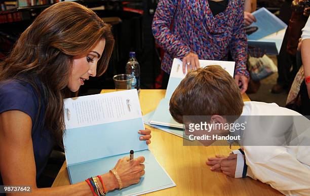 In this handout image provided by the Jordan Royal Household, Queen Rania of Jordan signs a copy of "The Sandwich Swap" in the United Nations...