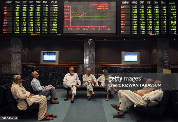 Pakistani stockbrokers discuss share prices during a trading session at the Karachi Stock Exchange on April 29, 2010. The benchmark KSE-100 index was...